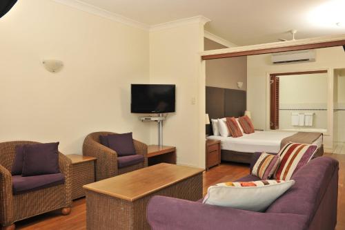 a hotel room with a bed and two chairs at Mantra on the Inlet in Port Douglas
