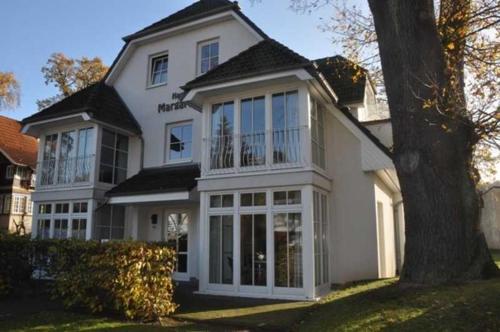 a white house with large windows and a tree at Haus Margarete in Binz