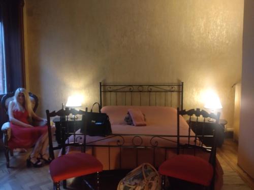 a woman sitting in a chair next to a bed at B&B Amarantha Gothica Genoa in Genova