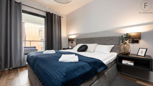 a bedroom with a large bed with a blue blanket at Flatbook - City Center Apartments Brabank with Parking in Gdańsk