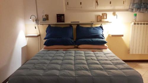 uma cama com almofadas azuis num quarto em Casa Zila em Finale Ligure