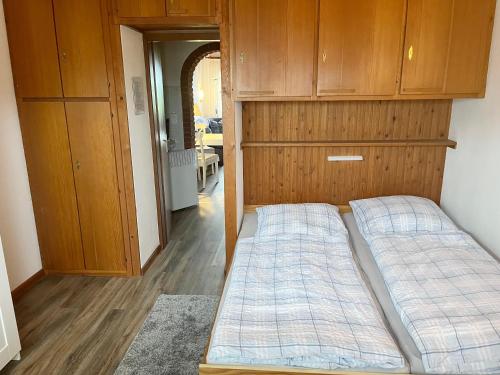 - 2 lits dans une chambre avec des armoires en bois dans l'établissement Haus Lith - Fewo Olesen, à Nordstrand