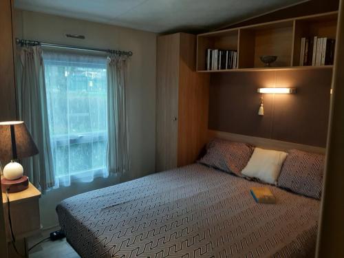 une petite chambre avec un lit et une fenêtre dans l'établissement Normandie 3 chambres Plages débarquement Mobile home, à Litteau