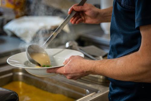 a man is holding a bowl in a kitchen at Hotel Fontána in Brno