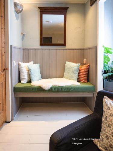 a bench in the corner of a room with pillows at De Stadsboerderij in Kampen