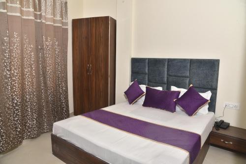 um quarto com uma cama grande e almofadas roxas em APEX HOTEL em Amritsar