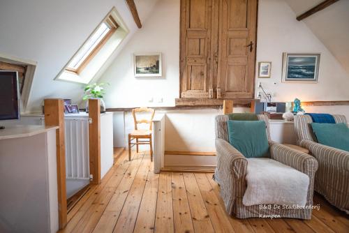 a living room with two chairs and a kitchen at De Stadsboerderij in Kampen