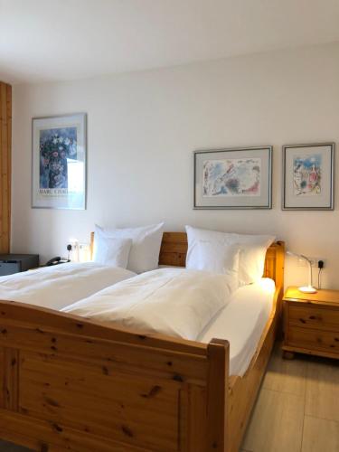 Un dormitorio con una gran cama de madera con sábanas blancas. en Hotel Sommerhaus Garni am See, en Bodman-Ludwigshafen