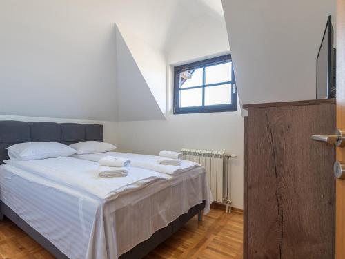 um quarto com uma cama com lençóis brancos e uma janela em Velika Recepcija 10 em Zlatibor