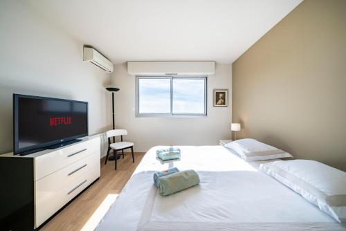 a bedroom with a large white bed and a flat screen tv at Baie Roquebrune, Balcon Vue Mer, Parking Gratuit - AO in Roquebrune-Cap-Martin