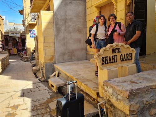 un grupo de personas de pie junto a un cartel con una maleta en Hotel Shahi Garh, en Jaisalmer