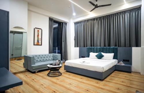 ein Schlafzimmer mit einem Bett und einem blauen Sofa in der Unterkunft HOTEL THE PARKER INN By KBNT GROUP in Surat