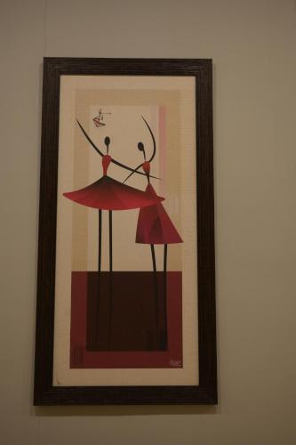 a framed picture of two women in red dancing at HOTEL THE PARKER INN By KBNT GROUP in Surat