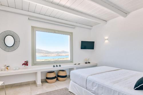 a white bedroom with a bed and a window at Antiparos Thea in Antiparos