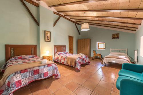 a bedroom with two beds and a blue couch at Rapia. Casa Rosa 2 in Moratalla