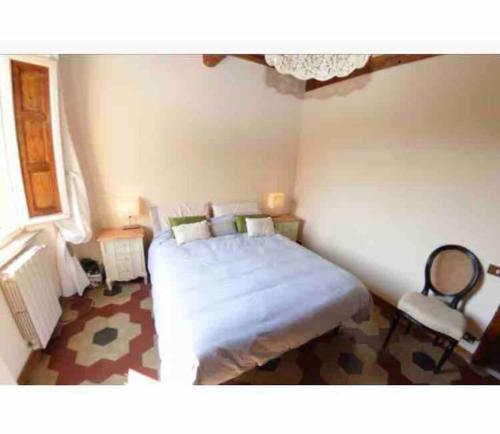 - une chambre avec un grand lit blanc et une chaise dans l'établissement Casamalu, à Lucques