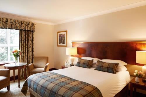 Pokój hotelowy z łóżkiem i krzesłem w obiekcie The Grange Manor w mieście Grangemouth