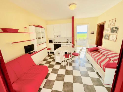 a living room with a red couch and a kitchen at Appartamento Eldorado in Marina di Bibbona