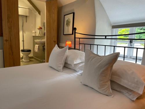 uma grande cama branca com almofadas brancas num quarto em Spring Cottage B&B em Probus