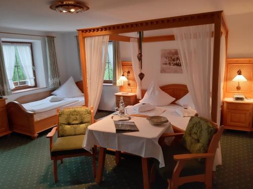 ビショフスヴィーゼンにあるLandhaus Degenのベッド、テーブル、椅子が備わるホテルルームです。