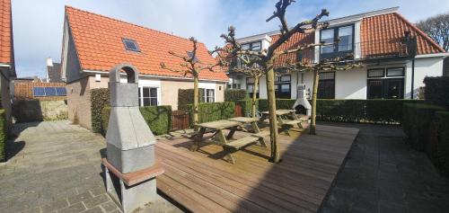 una terraza de madera con mesa de picnic frente a una casa en De Friese Antillen en Hollum