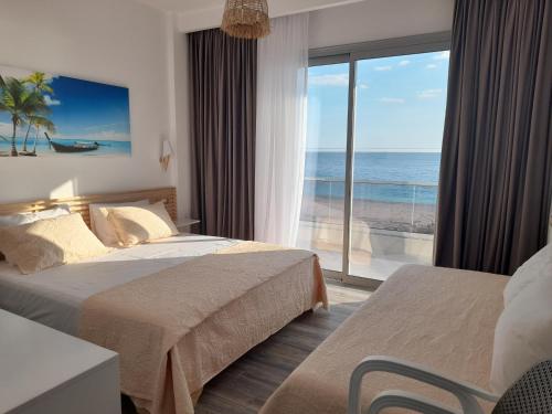 a hotel room with two beds and a view of the ocean at Anxhelos Hotel in Himare