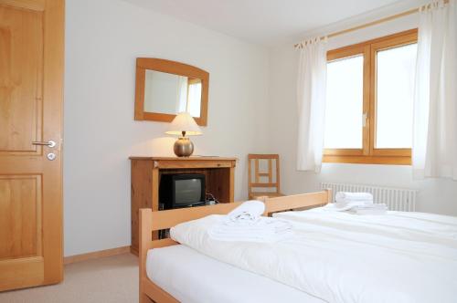 a bedroom with two beds and a mirror and a tv at Ambiente Bettmeralp | A10 in Bettmeralp
