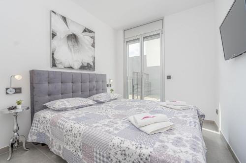 ein weißes Schlafzimmer mit einem Bett und einem Fenster in der Unterkunft Apart-rent Apartamento Av Platja Santa Margarita 2010 in Roses