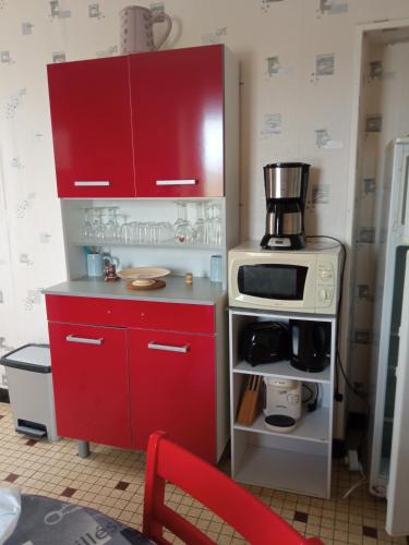 - une cuisine avec une armoire rouge et un four micro-ondes dans l'établissement Les Hortensias 26, à Saint-Laurent-sur-Mer