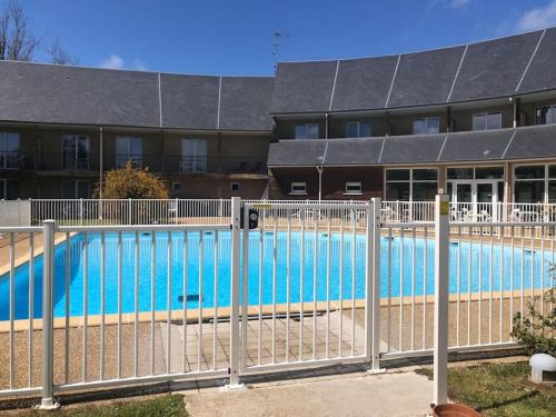 una valla alrededor de una piscina frente a un edificio en Appartement F2 calme et élégant, en Équemauville