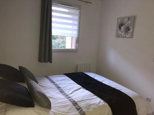 uma cama num quarto com uma janela em Appartement F2 calme et élégant em Équemauville
