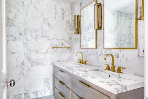 La salle de bains en marbre blanc est pourvue de 2 lavabos et d'accessoires en or. dans l'établissement 2BR Gowanus Townhouse w WD nr Prospect Park NYC-883, à Brooklyn