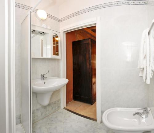 a white bathroom with a sink and a toilet at Albergo Garni Orchidea in Riva del Garda