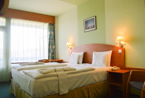 ショプロンにあるホテル シエスタの大きなベッド(白いシーツ付)が備わる客室です。