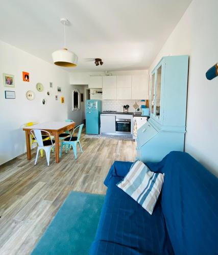 uma sala de estar com um sofá azul e uma mesa em MALU Bilo CON GIARDINO WIFI E POSTO AUTO IN CENTRO A SIROLO em Sirolo