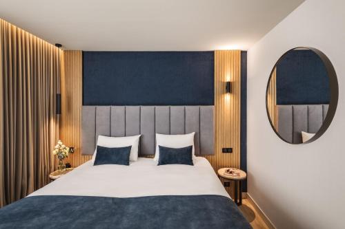 - une chambre avec un grand lit et un miroir dans l'établissement Hôtel & Spa Le Maury, Vannes, The Originals Boutique, à Vannes