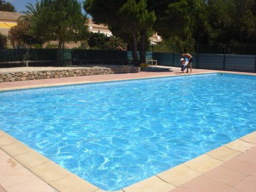 - une grande piscine bleue avec une femme et un enfant dans l'établissement Studio Cabine avec Terrasse, Piscine et Parking Privé, 4 Couchages à Narbonne Plage - FR-1-229B-62, à Narbonne