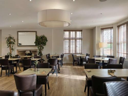 a restaurant with tables and chairs and a chandelier at Linton Lodge a BW Signature Collection Hotel in Oxford