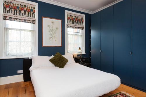 a bedroom with blue walls and a white bed at Veeve - Sunshine Botanical in London