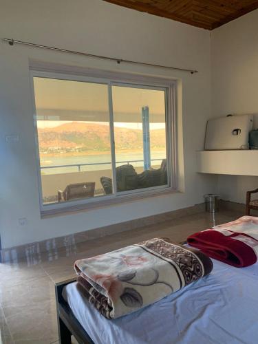 a bedroom with a bed and a large window at PINETOP RESORT in Khanpur