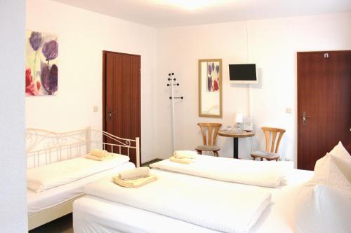 two beds in a room with a table and chairs at Pension An der Kamske, 3BZ 2 in Lübbenau
