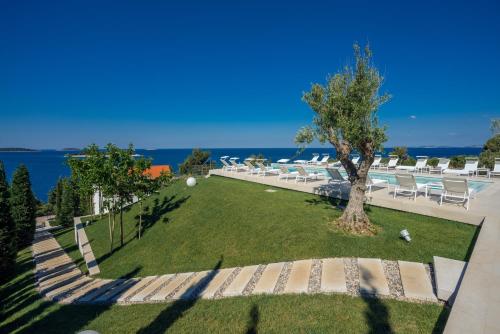 a park with a tree and chairs and the water at Golden Rays Luxury Villas & Apartments in Primošten