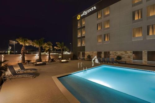 una piscina di fronte a un hotel di notte di La Quinta Inn & Suites by Wyndham Del Rio a Del Rio