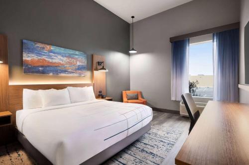 a bedroom with a large white bed and a desk at La Quinta Inn & Suites by Wyndham Del Rio in Del Rio