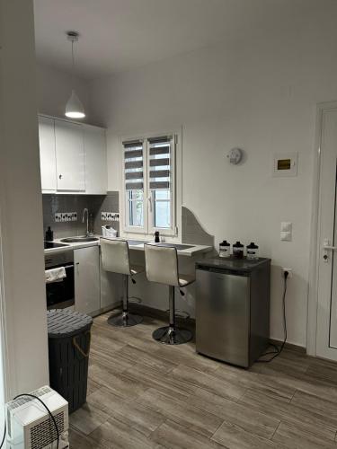 a kitchen with white cabinets and a table and chairs at Dominik apartment in Patmos