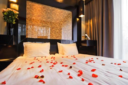 a bed with red rose petals on it at Platinum Palace Boutique Hotel & SPA in Wrocław