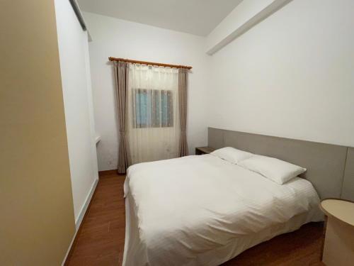 a bedroom with a white bed and a window at Jiufen Gourd Stone TreeHouse 137 in Ruifang