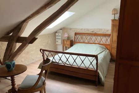 een slaapkamer met een bed en een stoel op zolder bij Cottage Ker Bunny à Feraillou 