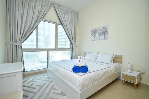 ein Schlafzimmer mit einem weißen Bett mit einem Blu-ray-Player in der Unterkunft Cozy 1 Bedroom with Study room in Dubai Marina - Ideal for 3 Guests - PRK in Dubai