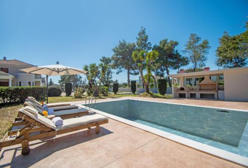 a swimming pool with two lounge chairs next to a house at Adriana di Levante by "elite" in Ayios Kirikos